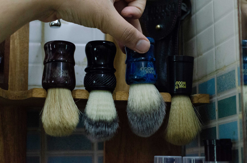 Shaurya picking a Pink Woolf shaving brush from the 4 available brushes from a custom made shaving accessories stand.