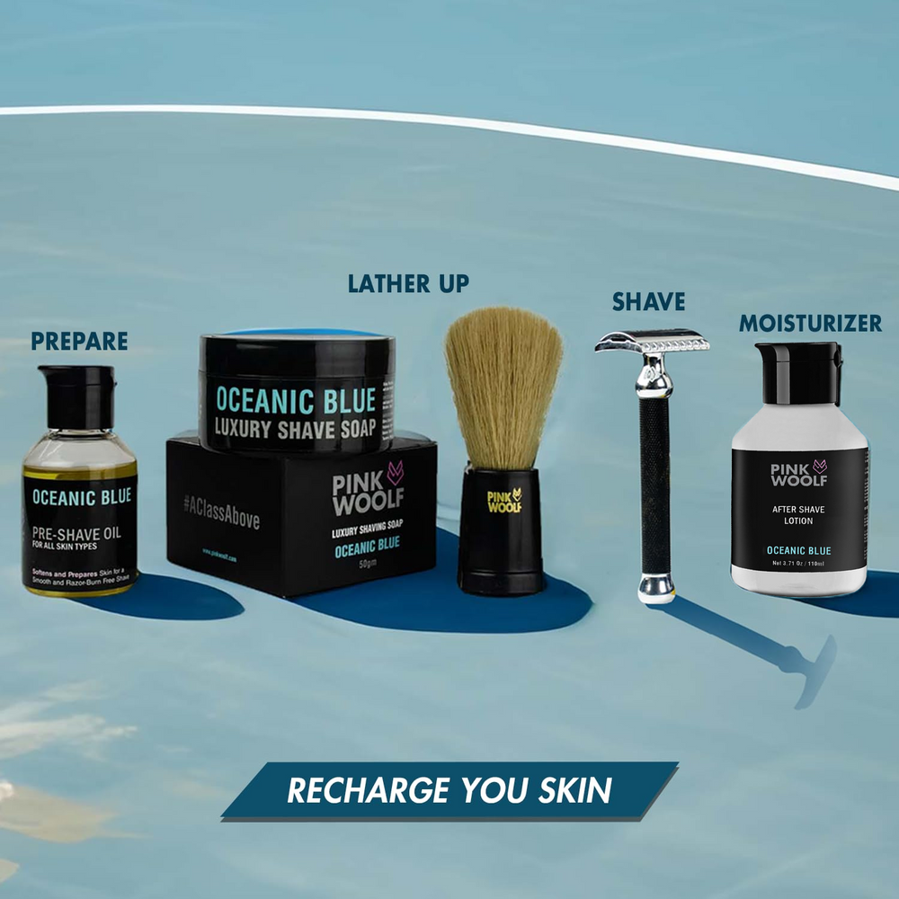 Collection of men's grooming products including a jar, brush, razor, and bottles on a blue background.
