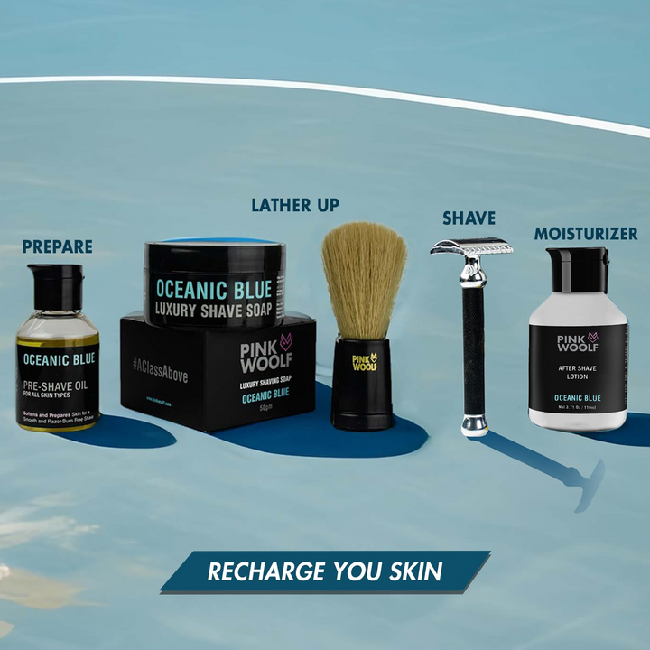 Collection of men's grooming products including a jar, brush, razor, and bottles on a blue background.