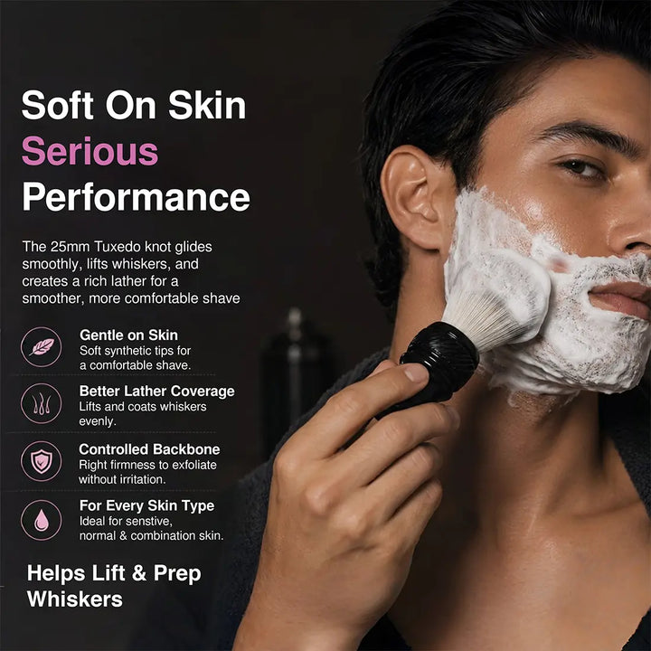 A man with white shaving foam on his face uses a black-handled facial cleansing brush against his cheek. The image includes marketing text on the left describing soft-on-skin performance and benefits, with a dark studio background.